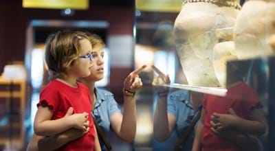 Archäologische Sammlung Zwei Kinder betrachten Ausstellungsstück hinter Glas