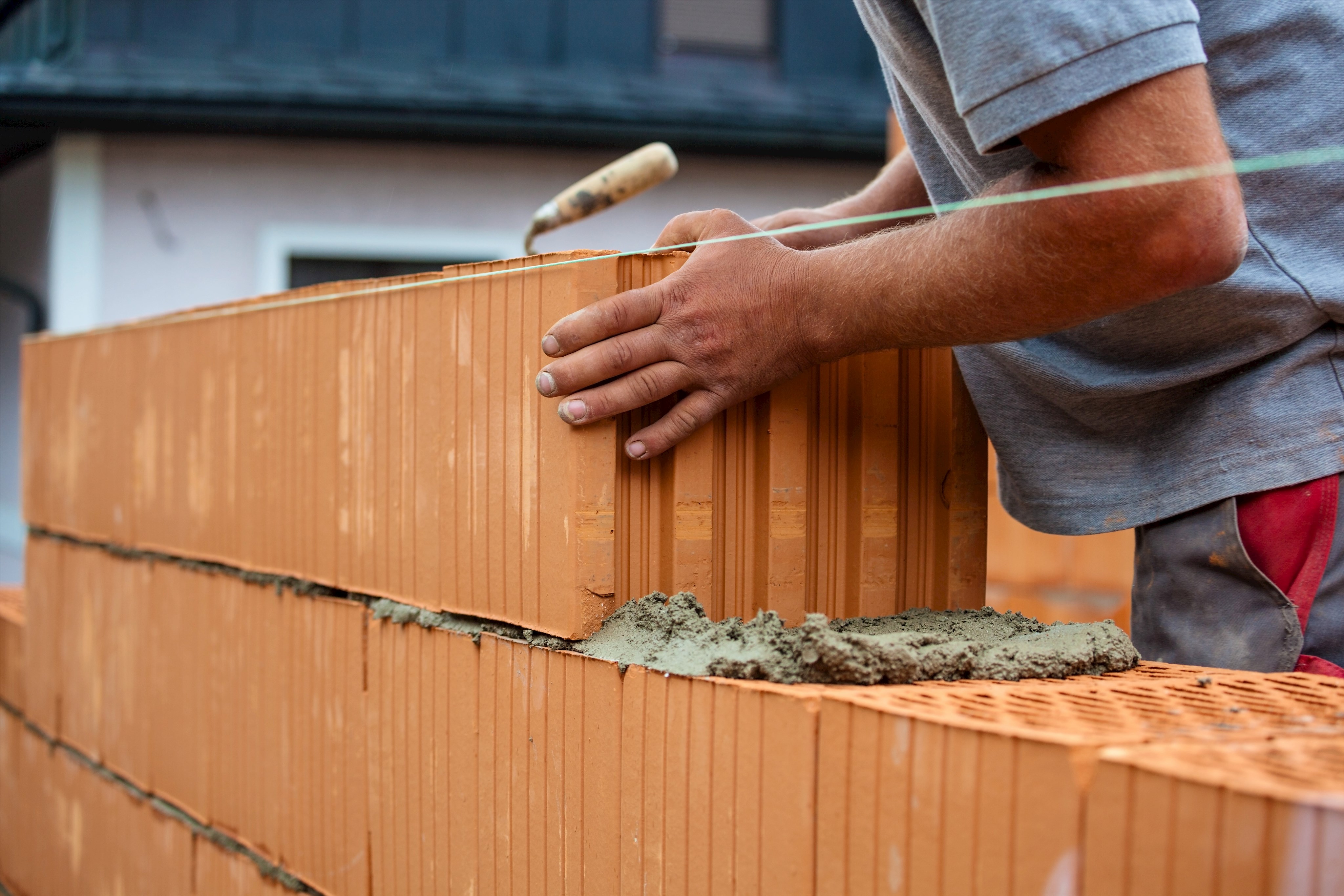 Handwerker baut Mauer mit Ziegeln